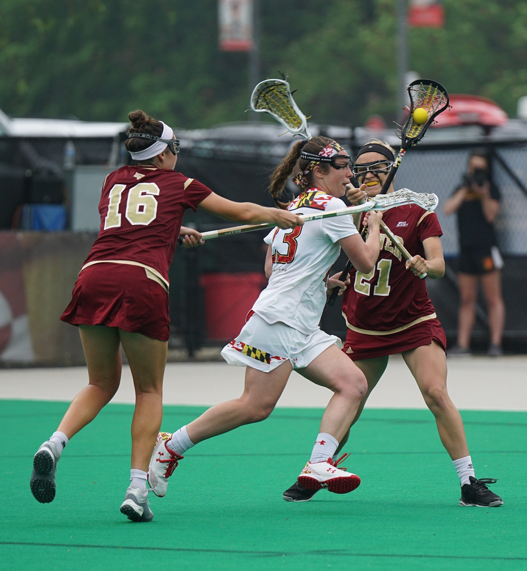 Three young women playing an intense game of lacrosse.