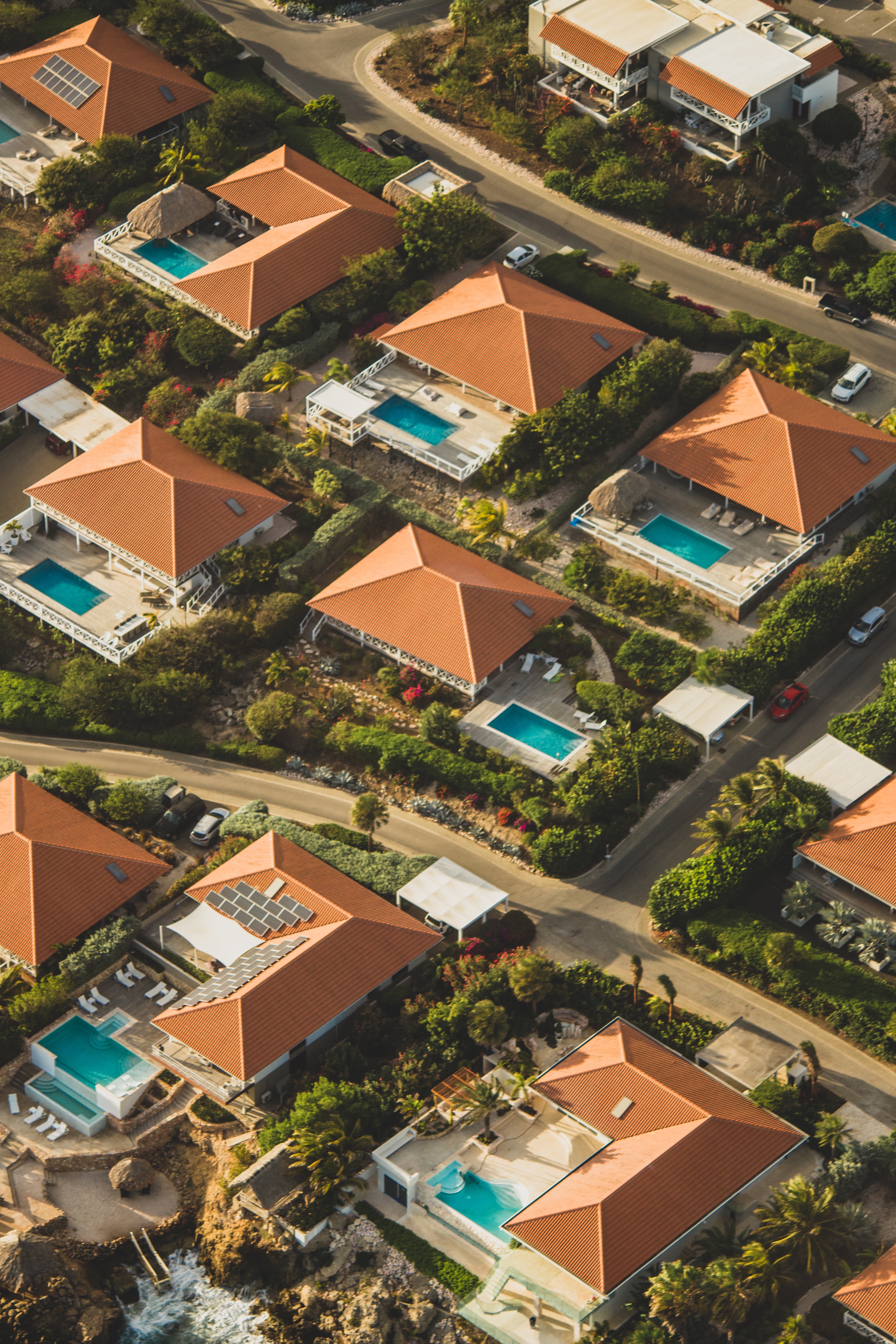 A residential area where all the homes have the same terracotta roofs and rectangular, turquoise pools.