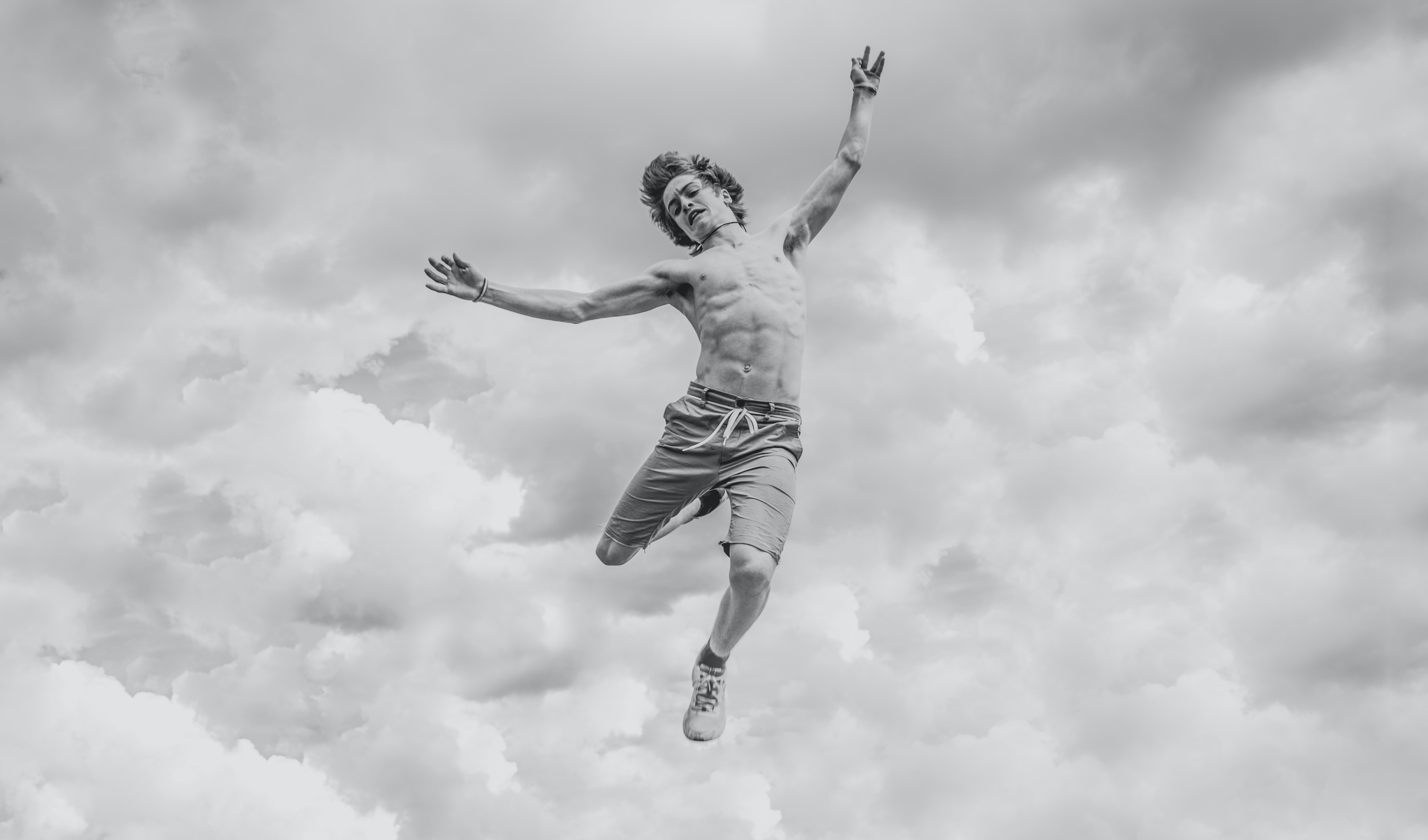 A man with flailing arms and legs that appears to be falling from the cloudy sky above.